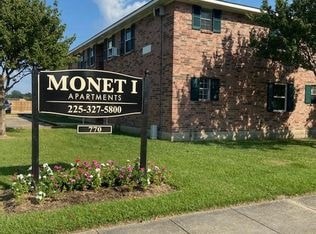 A sign for Monet I Apartments is in front of a brick building.