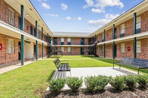 A courtyard with a bench and a green lawn.