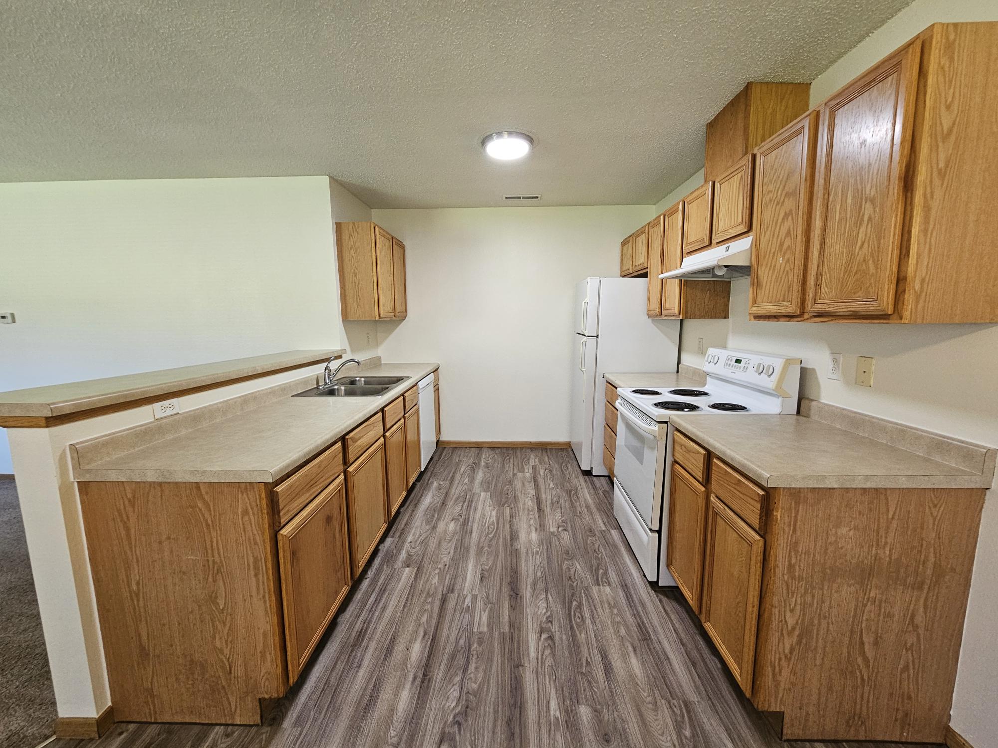 A kitchen with wooden cabinets and a white stove top oven.