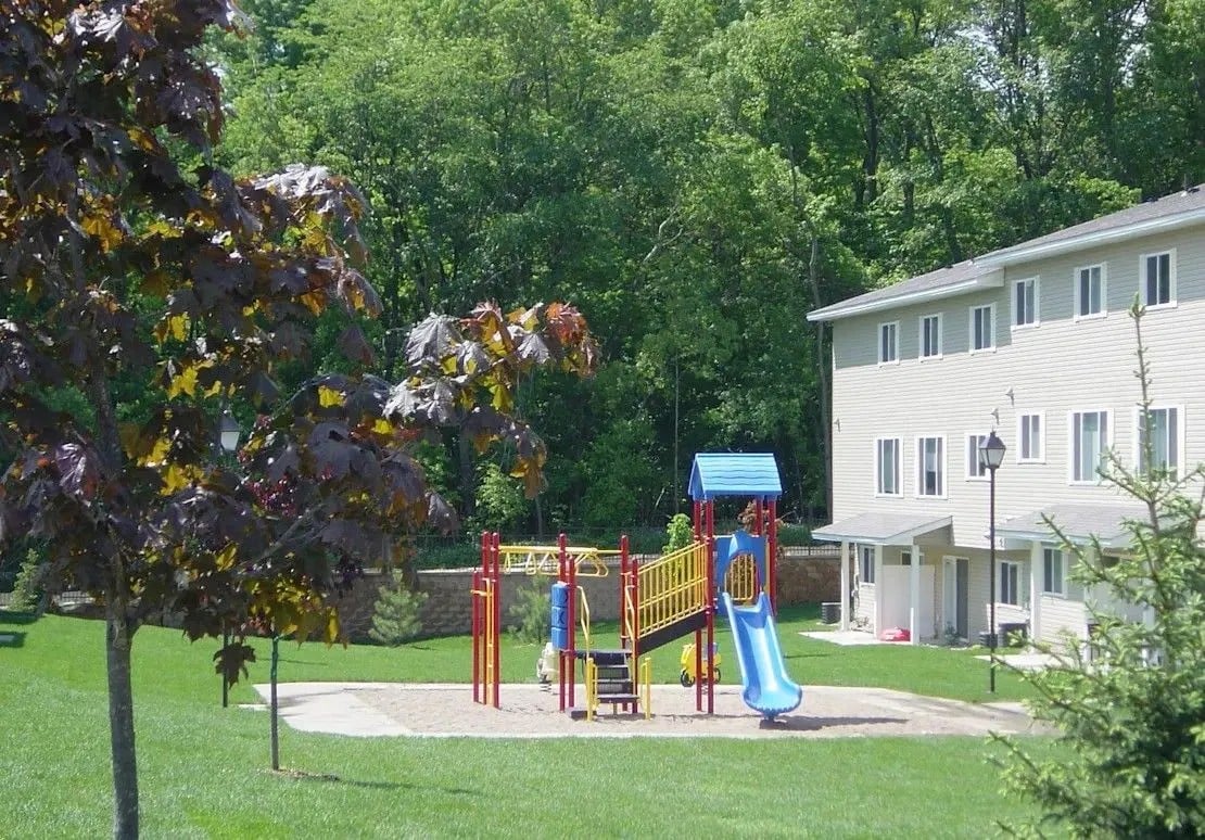 A playground with a blue slide and a yellow and red swing set.