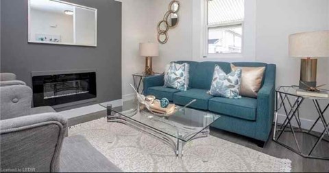 A living room with a blue couch, a fireplace, and a glass coffee table.