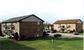 A building with a black roof and a parking lot in front.
