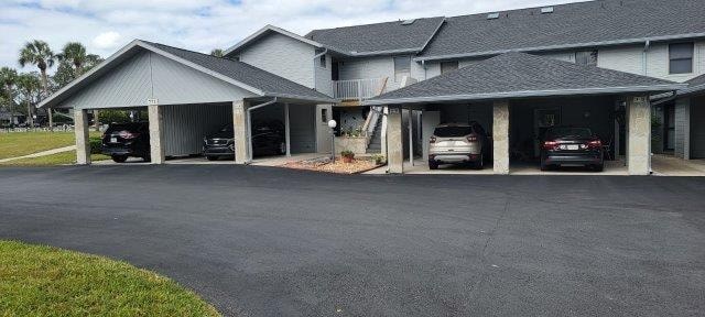 A carport with three cars parked in it.