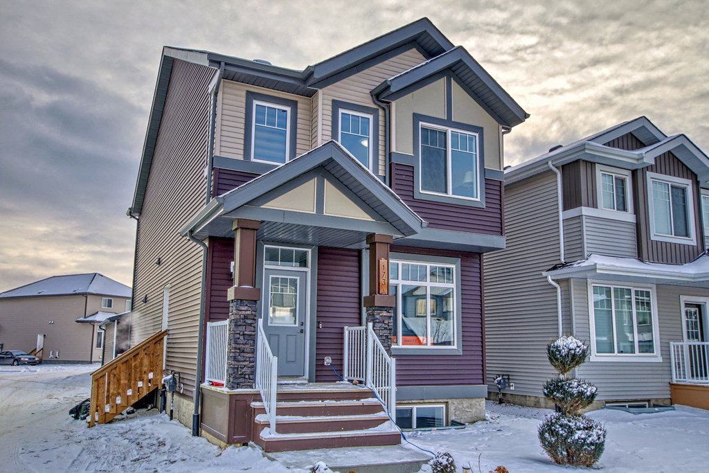 A house with a brown and grey exterior and a red door.