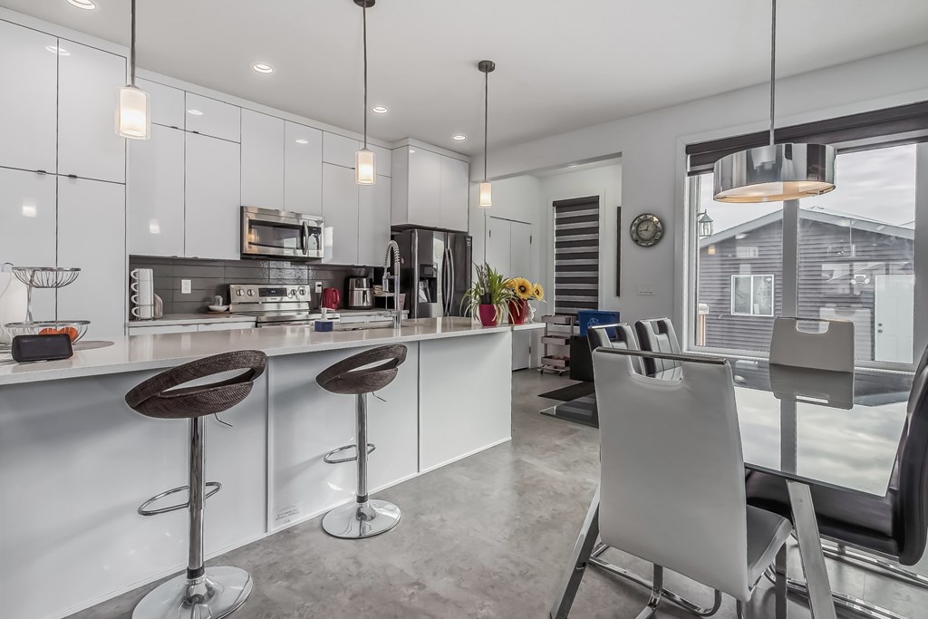 A modern kitchen with white cabinets and a bar area.