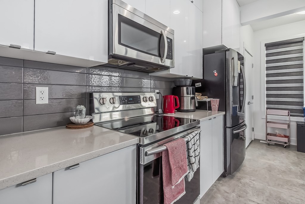 A modern kitchen with a black refrigerator and stainless steel appliances.