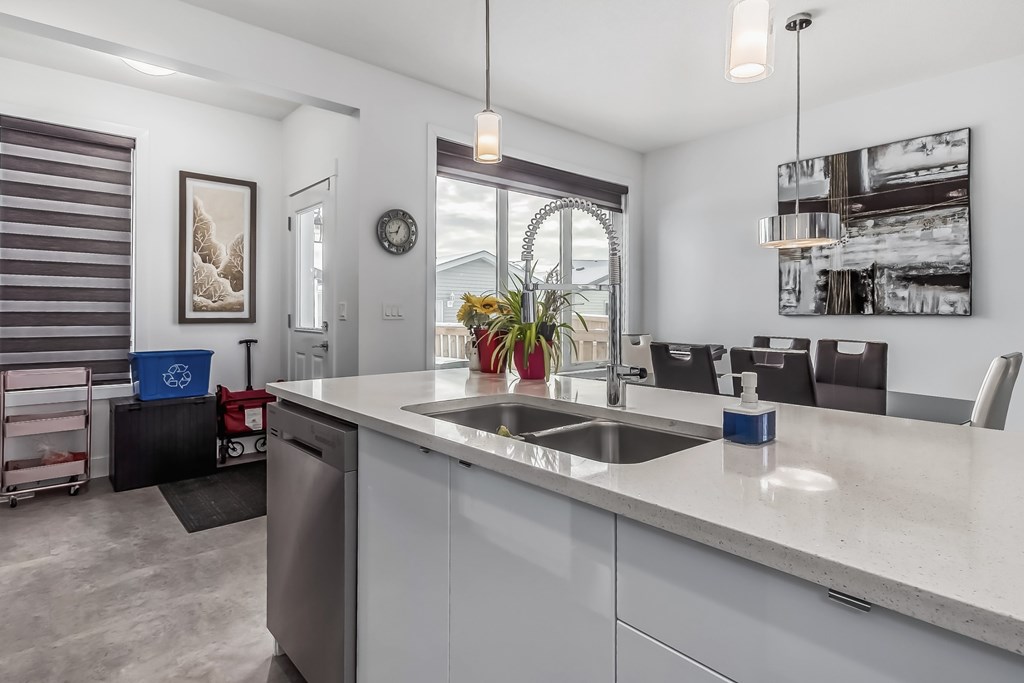 A modern kitchen with a large island and a dining area in the background.