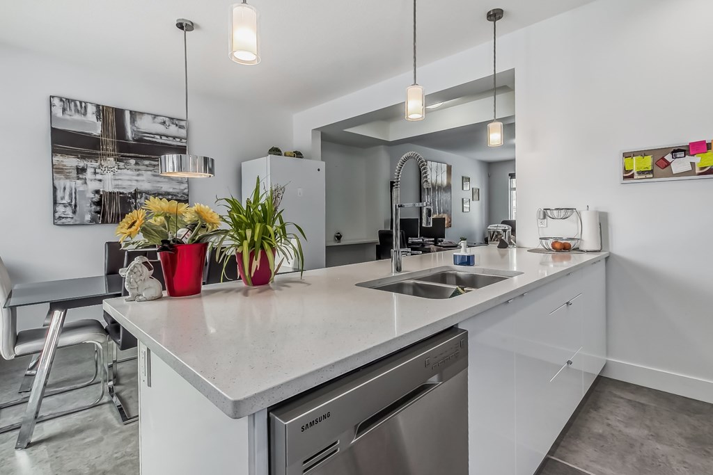 A modern kitchen with a stainless steel dishwasher and a white countertop.