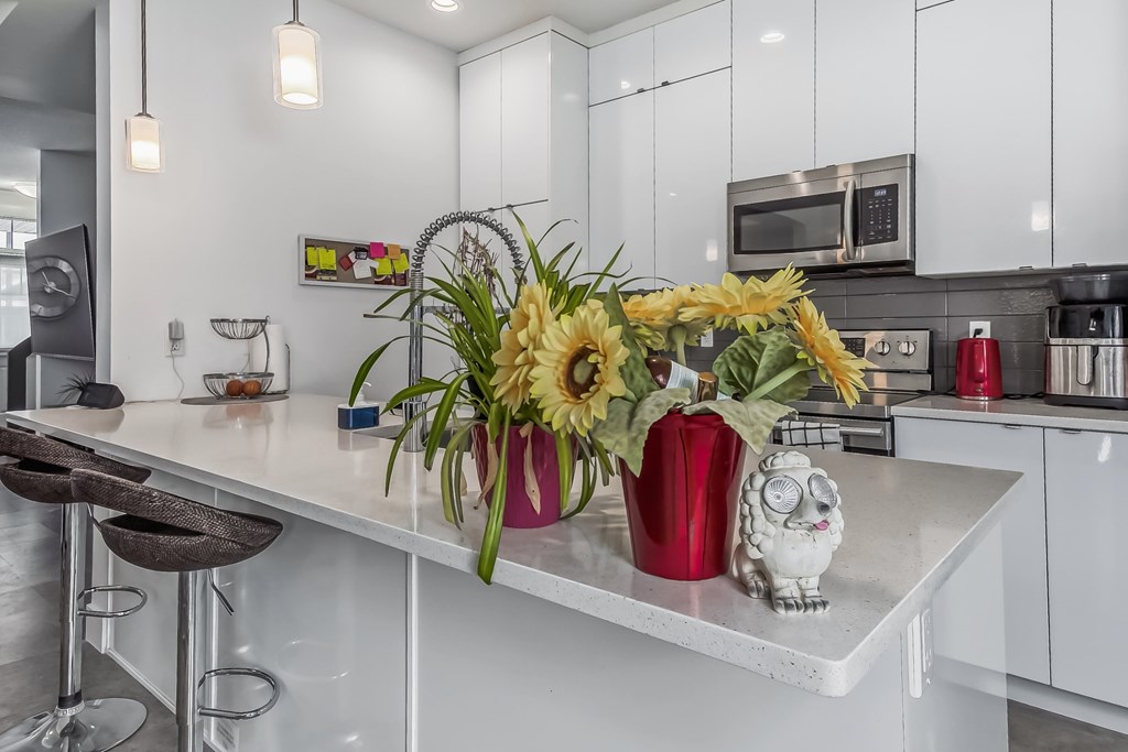 A kitchen with a white countertop and a vase of sunflowers.