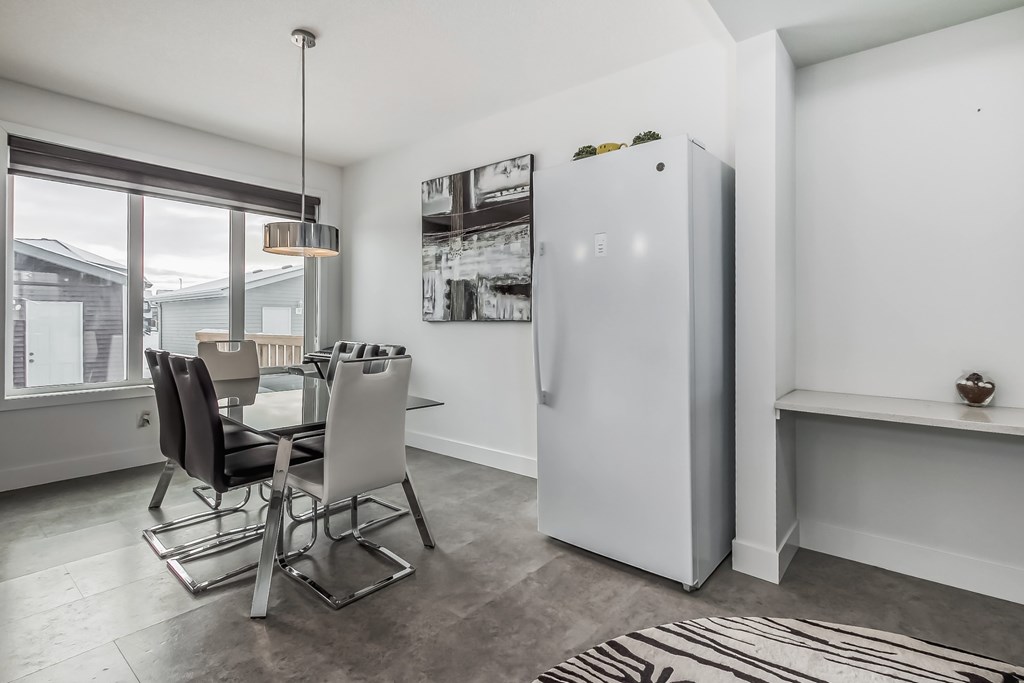 A white refrigerator is in a kitchen with a black and white rug on the floor.