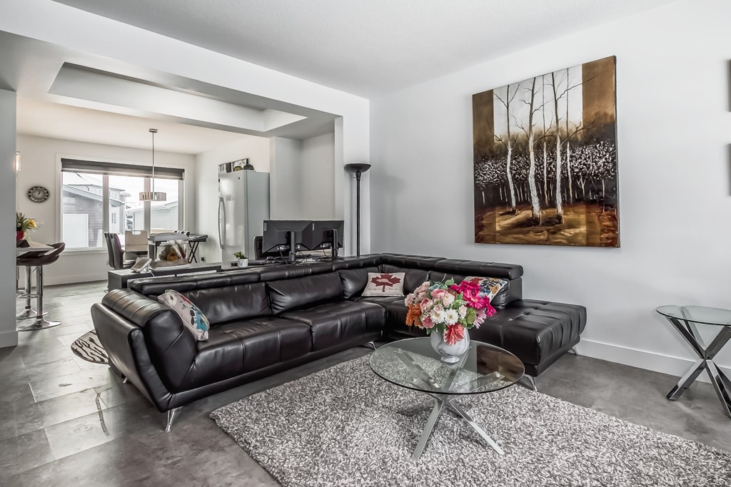 A black leather couch sits in a living room with a glass coffee table in front of it.