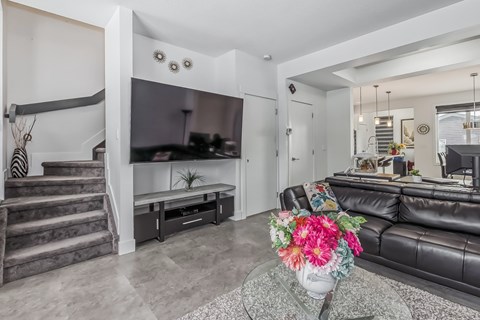 A living room with a black leather couch and a coffee table with flowers on it.