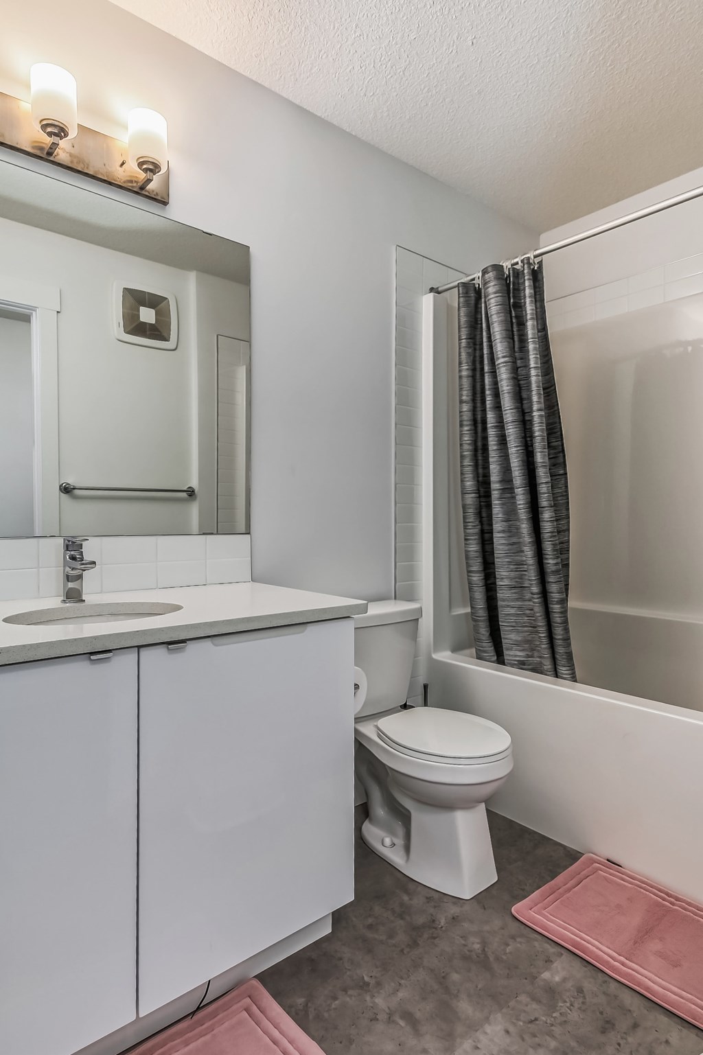 A white bathroom with a toilet, sink, and mirror.