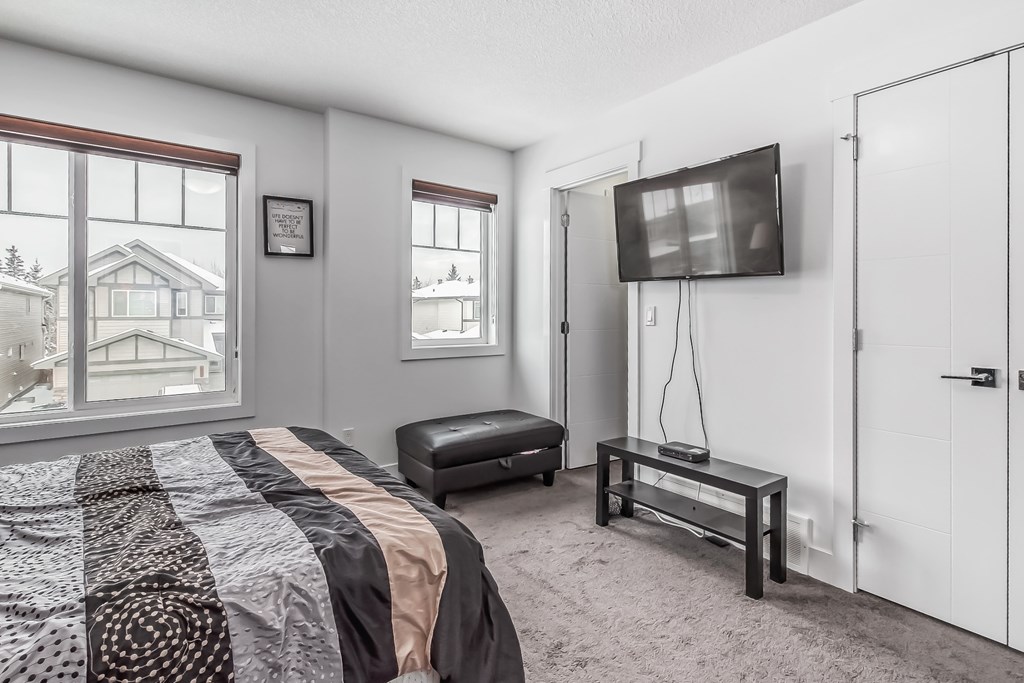 A bedroom with a large bed and a flat screen TV mounted on the wall.