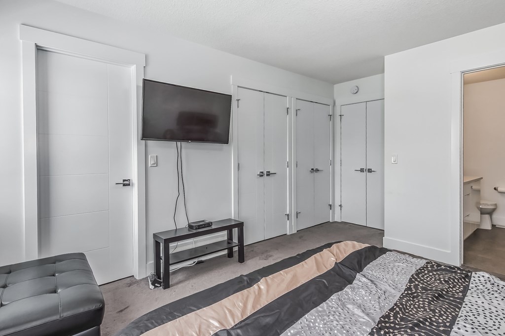 A bedroom with a bed, a chair, and a television.