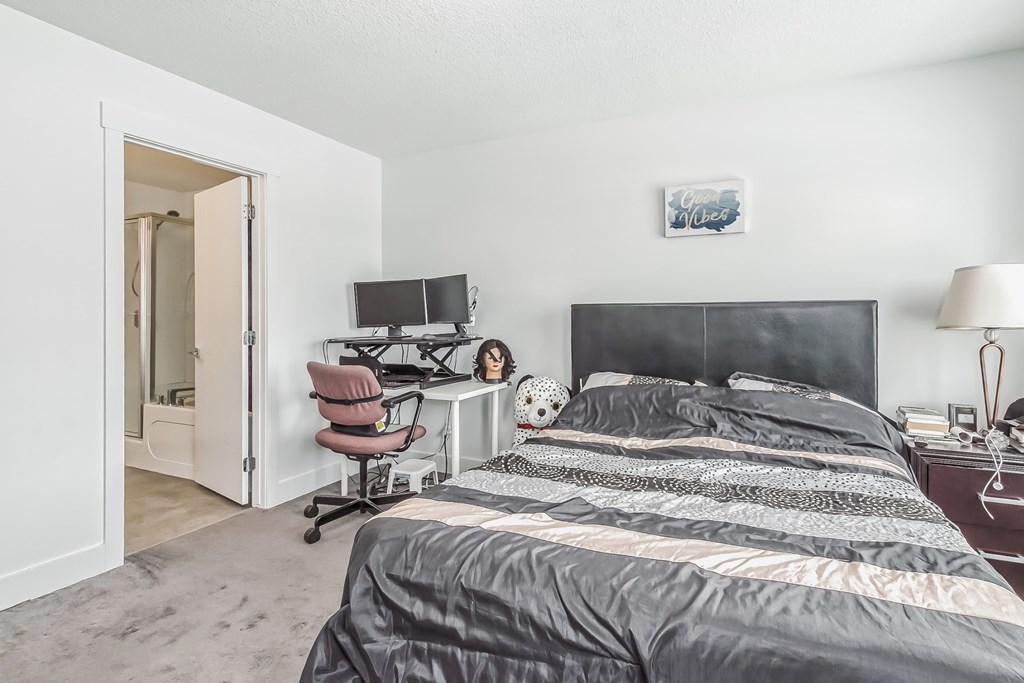 A bedroom with a bed, desk, and chair.