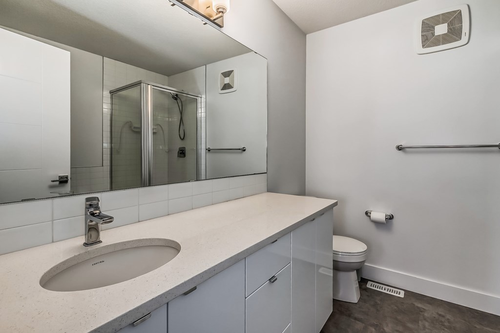 A bathroom with a sink, mirror, and toilet.