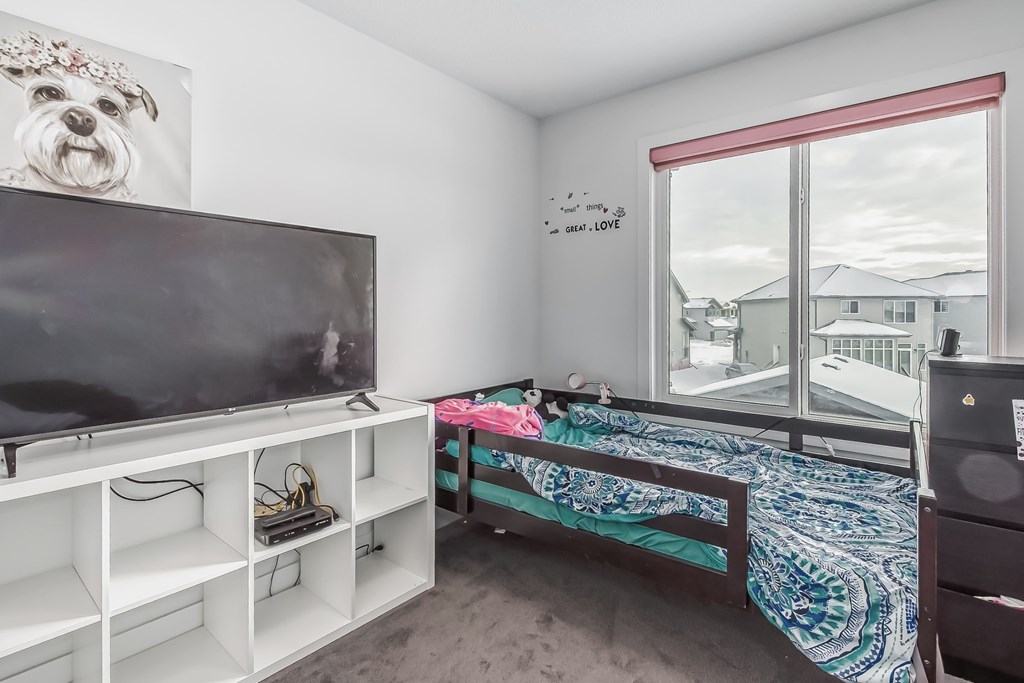 A room with a bed, a television, and a window.