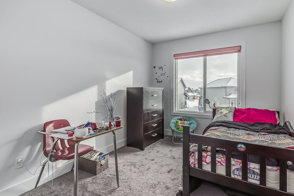 A bedroom with a bed, dresser, and chair.