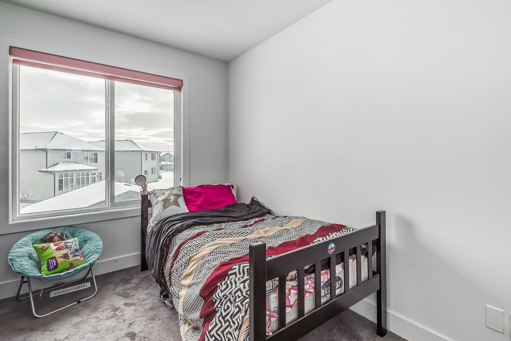 A bedroom with a bed, a chair, and a window overlooking a snowy landscape.