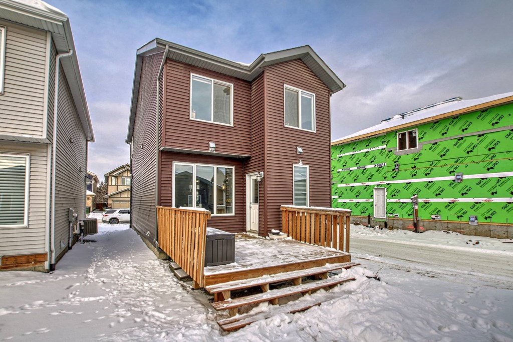 A house with a brown exterior is surrounded by snow.
