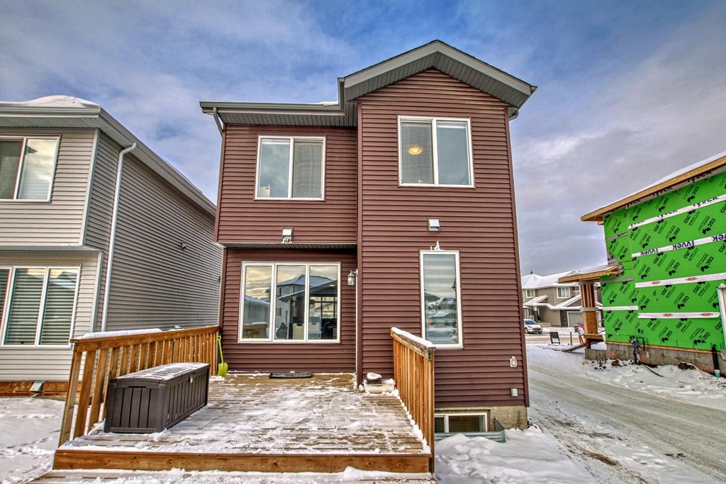 A house with a brown exterior is surrounded by snow.