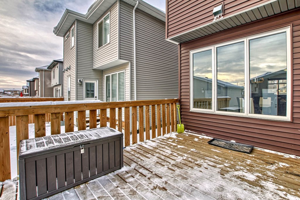 A house with a brown deck and a black mailbox.