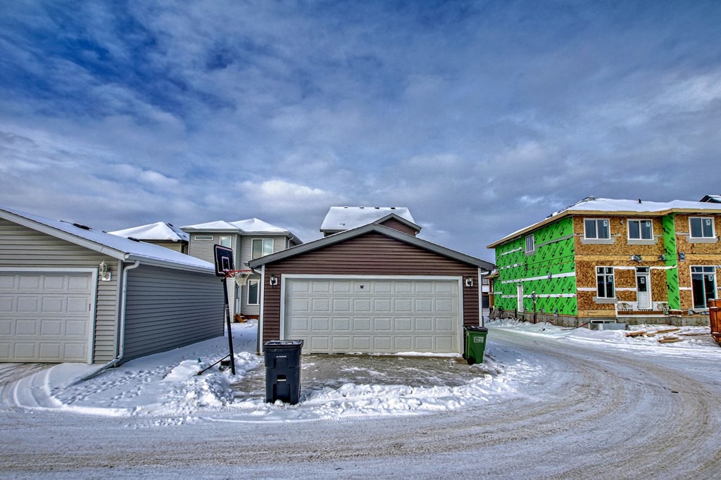 A residential area with houses and garages covered in snow.