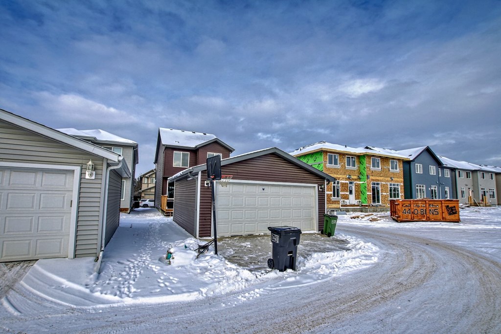 A snowy residential street with houses on either side.
