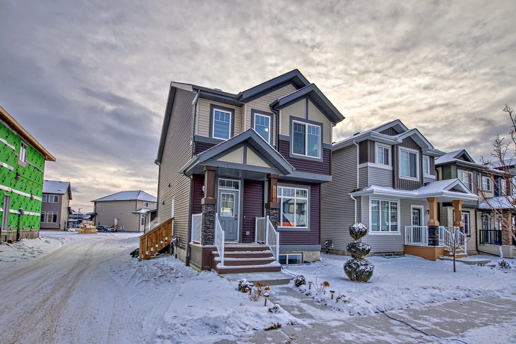A house with a grey and brown exterior is surrounded by snow.
