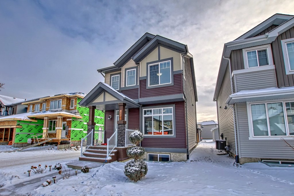 A house with a brown roof and a grey wall is surrounded by snow.