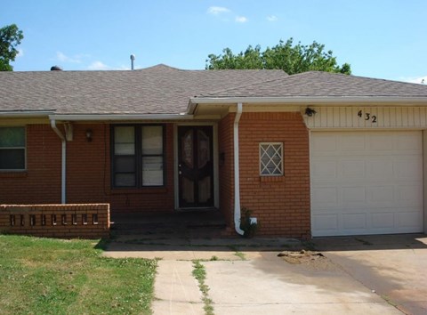A red brick house with a white garage door and a number 32 on the front.