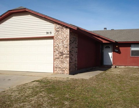 A red house with a white garage door and number 213 on the side.