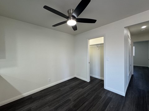 A room with a ceiling fan and a doorway leading to another room.