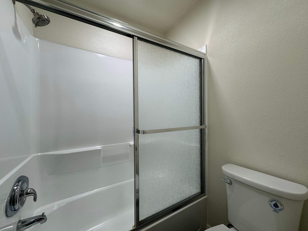 A white bathroom with a glass shower door.