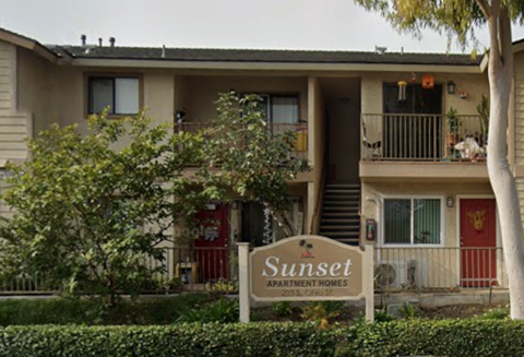 The image shows a building with a sign that reads "Sunset Apartment Homes.".