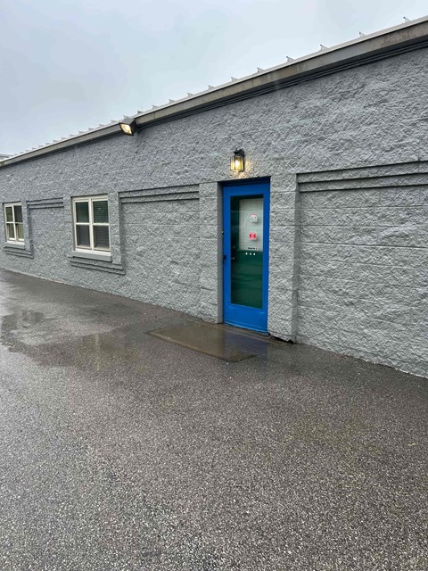 A grey building with a blue door and windows.