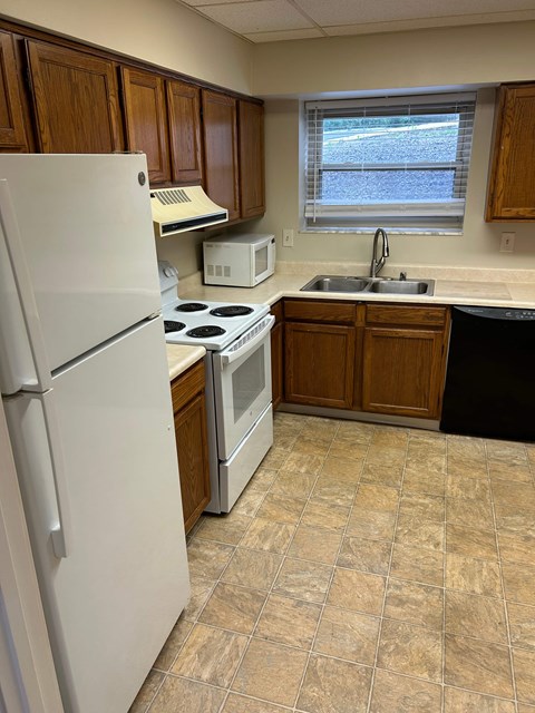 A kitchen with a white refrigerator, a stove, a microwave, and a sink.