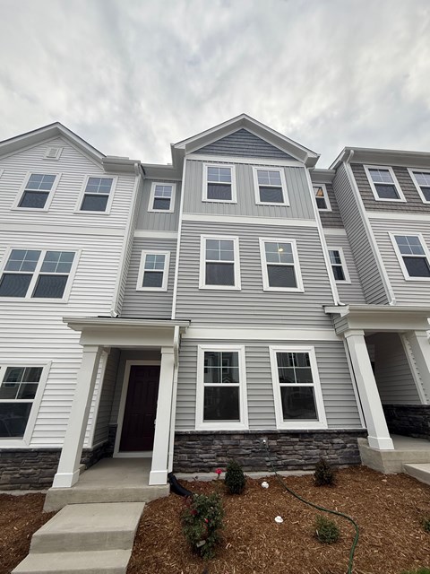 A grey and white two story house with a brown door and windows.