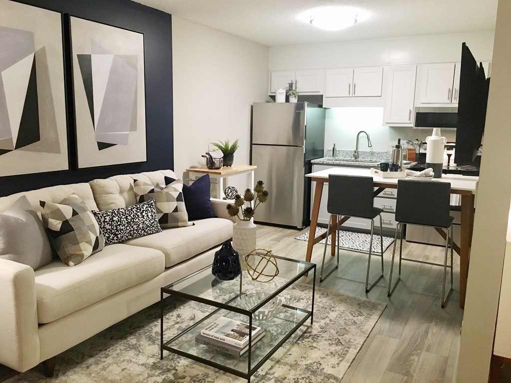 A modern living room with a glass coffee table and a white couch.