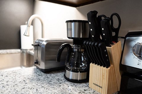 A kitchen counter with a toaster, knives, and a coffee maker.