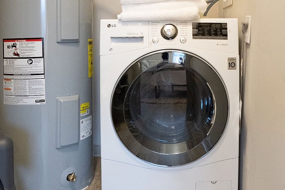 A white LG front load washing machine with a white towel on top of it.