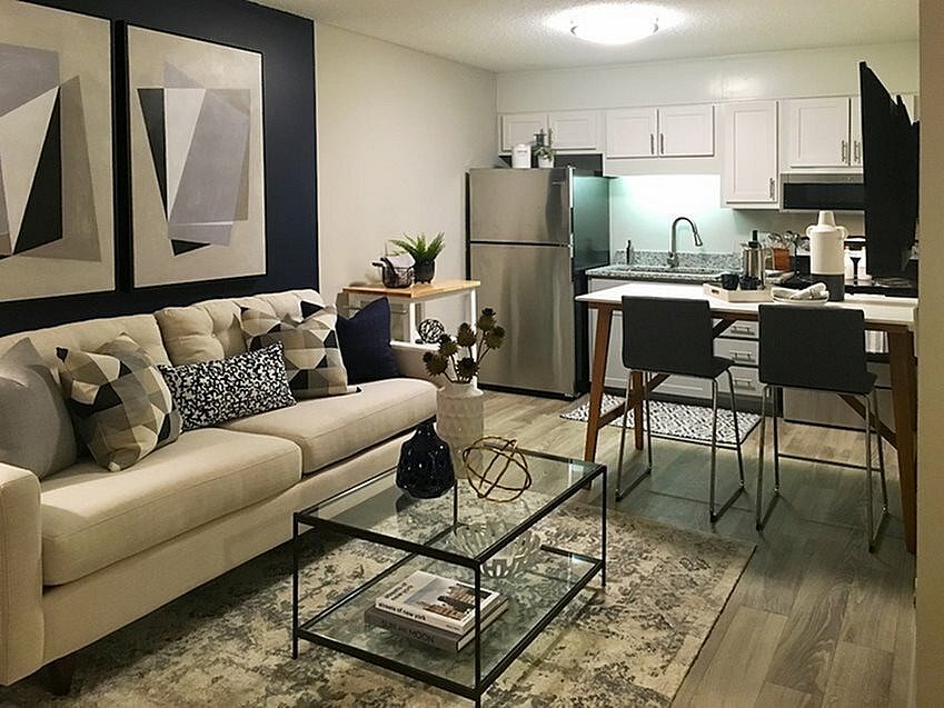 A modern living room with a couch, coffee table, and kitchen area.
