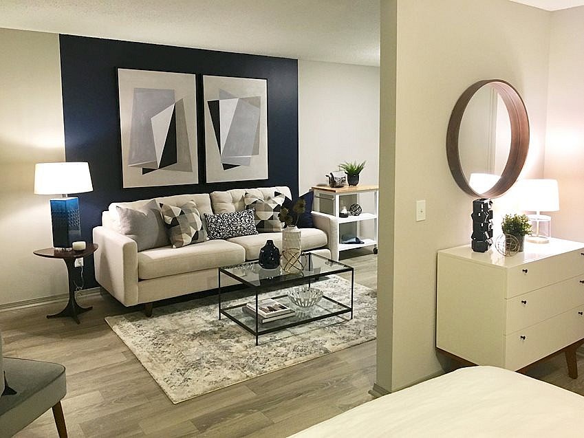 A living room with a white couch, a coffee table, and a side table with a lamp.