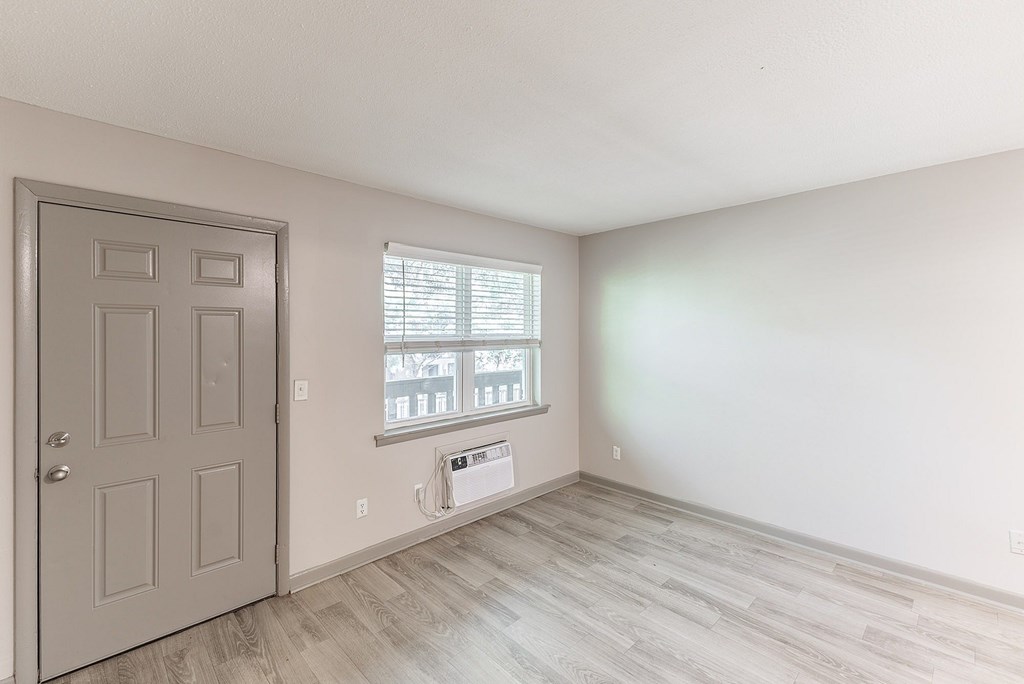 A room with a door and a window with blinds.