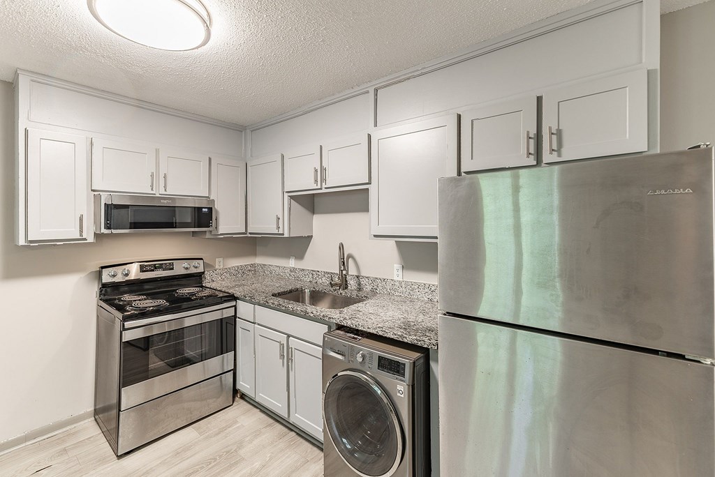 A kitchen with a stove, oven, microwave, sink, and refrigerator.