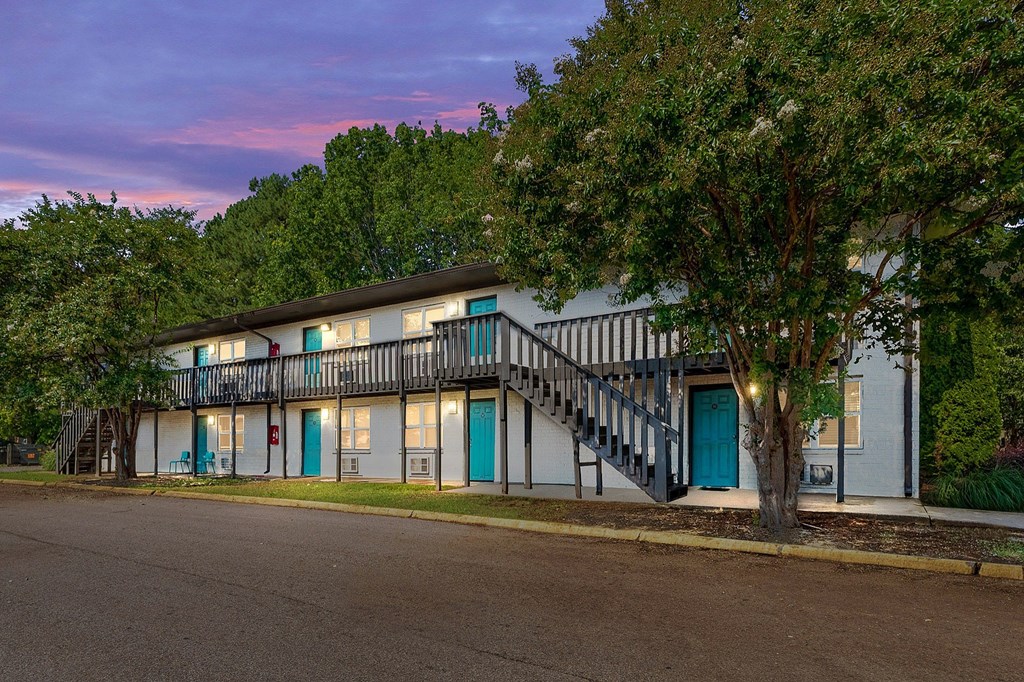 A building with a blue door and windows is surrounded by trees.