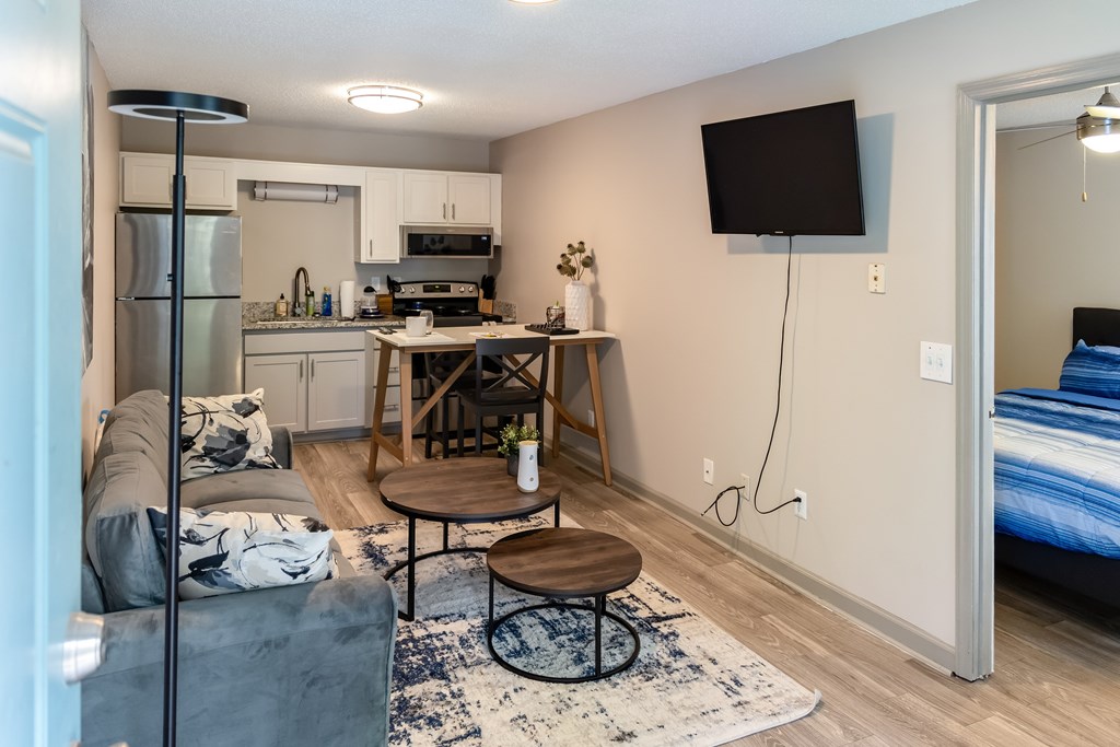 A living room with a grey couch and a television on the wall.