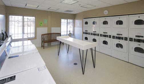 a large laundry room with many washers and dryers and a table