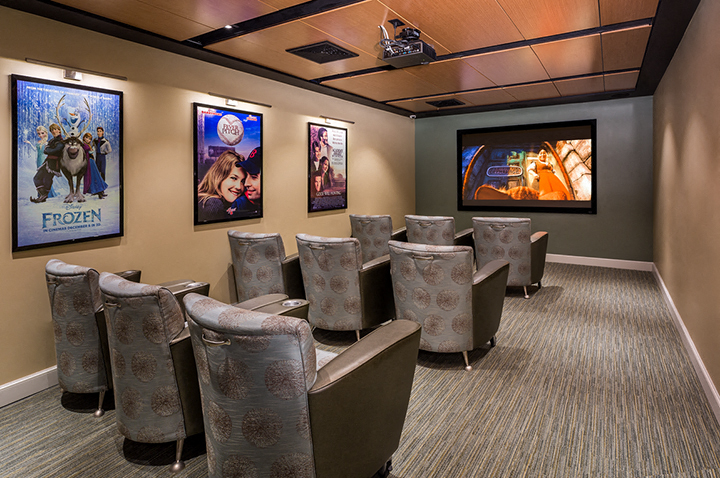 a conference room with chairs and a projector screen and pictures on the wall